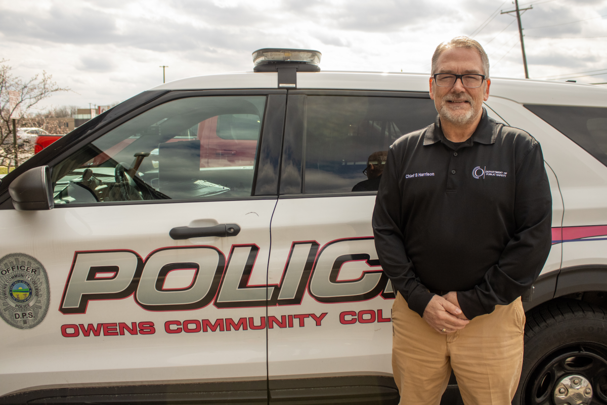 Owens Community College Chief of Police, Steve Harrison, takes a moment by an Owens Community College Police Automobile. 