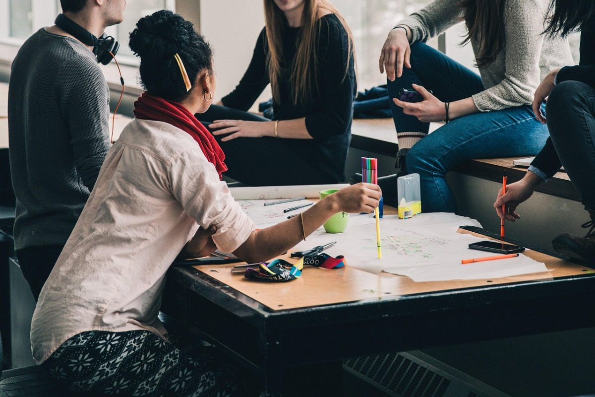 Students gathering and discussing assignments for an upcoming class.  Retrieved from Pixabay by StockSnap.